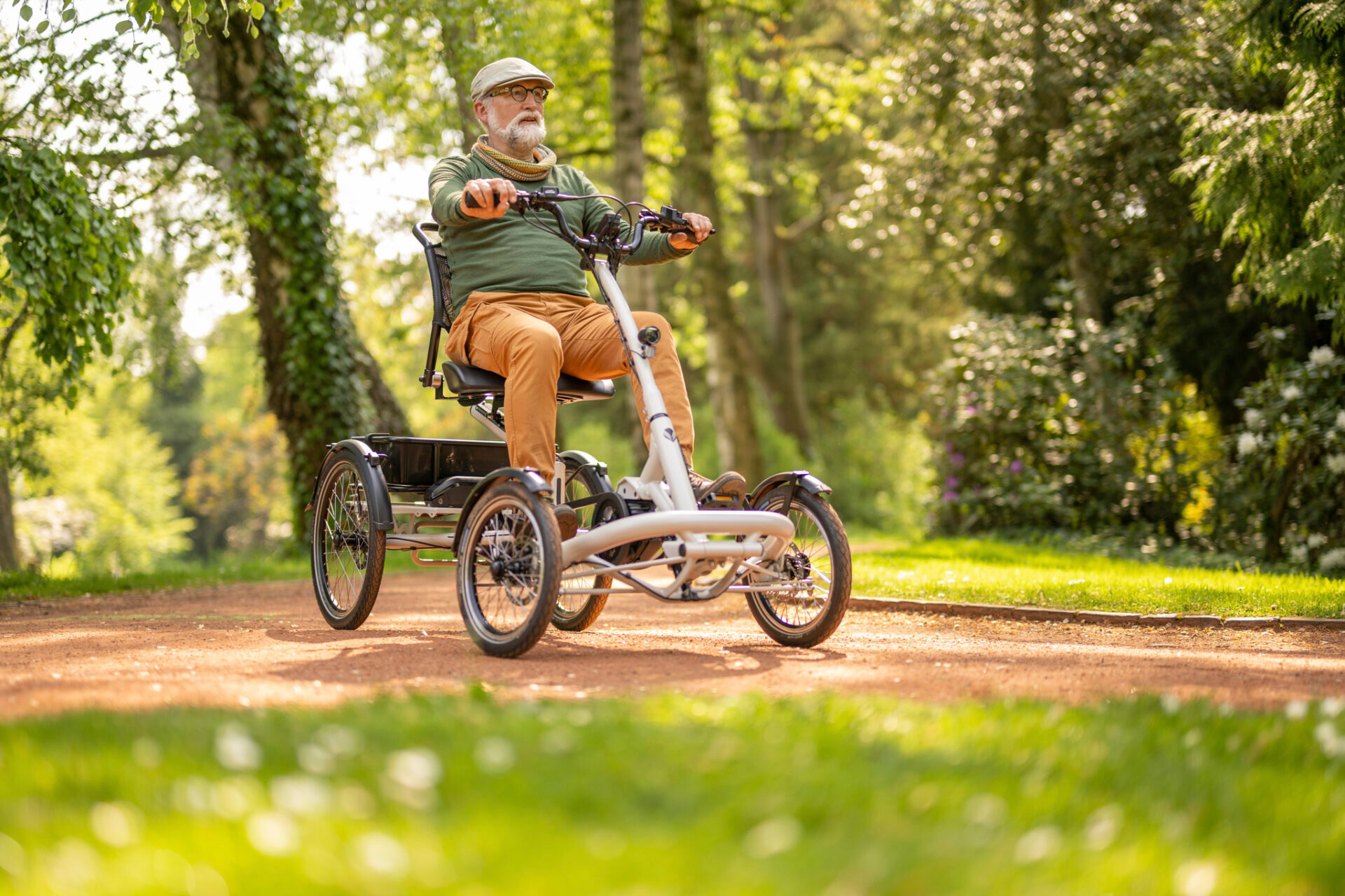 Volwassen man rijdt op een Pfau-Tec Tibo Plus driewielfiets over een bospad en geniet van stabiel en comfortabel fietsen.